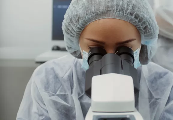 실험실에서 한 여성이 현미경을 들여다보고 있습니다.