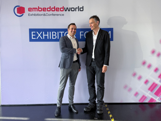Embedded World 전시회 벽 앞에서 악수를 나누고 있는 두 명의 매니징 디렉터