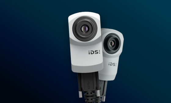 파란색 배경에 두 대의 IDS uEye XC 산업용 카메라.
